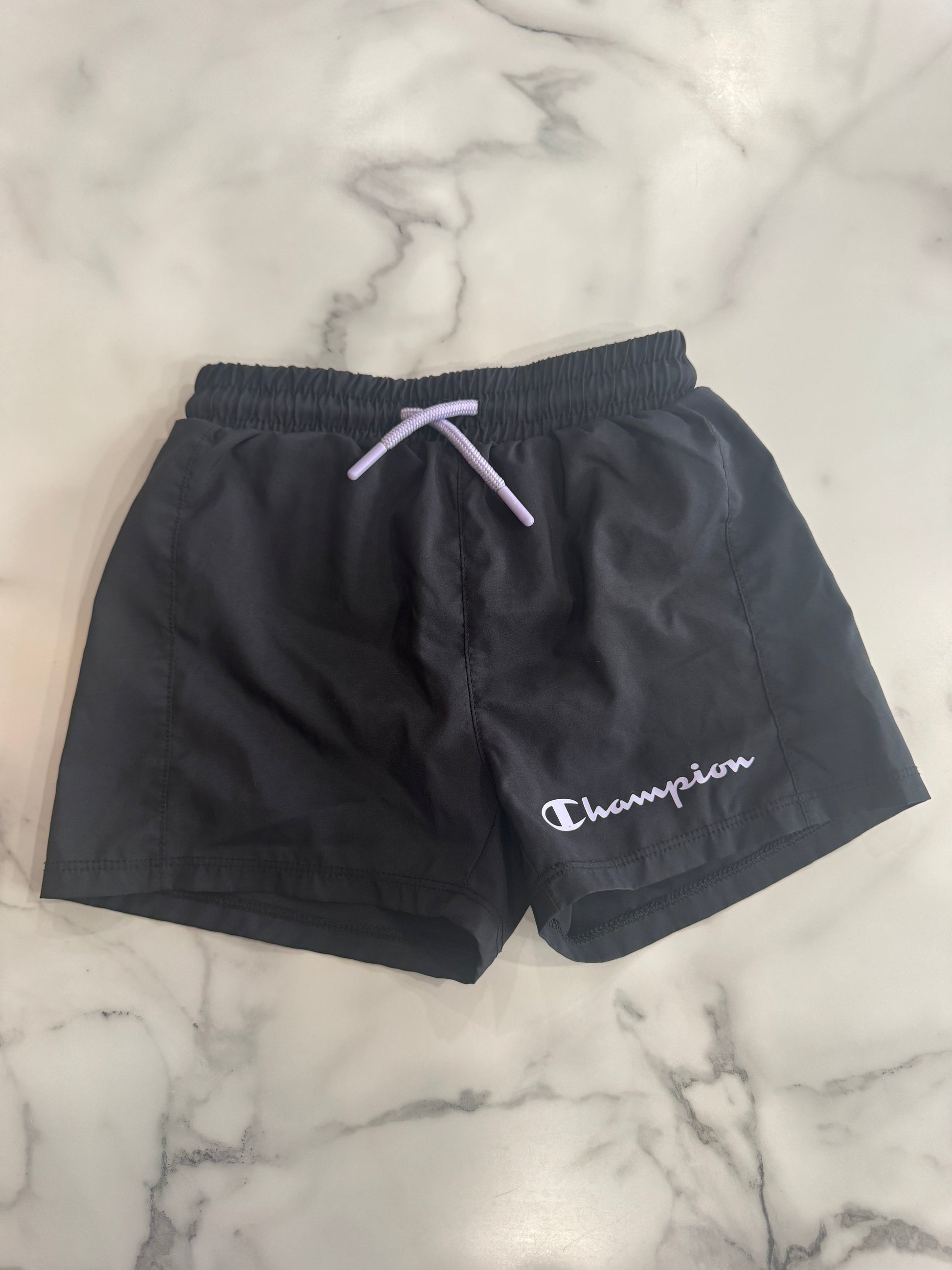 Black shorts with a brand logo on a marble surface